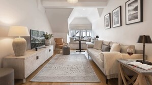 Ein modernes Wohnzimmer mit Sofa, Couchtisch, Teppich und einem Essbereich mit Tisch und Stühlen.