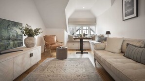 Ein moderner Loft-Wohnraum mit hoher Decke, großem Fenster, einer Couch, einem Fernseher und einem Essbereich.