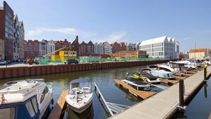 A marina with boats docked along the water, surrounded by buildings with distinct architectural styles. - Elite Apartments Szafarnia King Size (Gdansk)