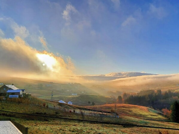 A rural landscape with rolling hills, a few houses, and a railway track. - Keepers (Alston)