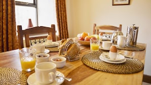 Una mesa de desayuno dispuesta con diversos alimentos, como huevos, fruta y bebidas.