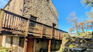 Un edificio de piedra con un balcón de madera, una puerta y una mesa de picnic al frente.