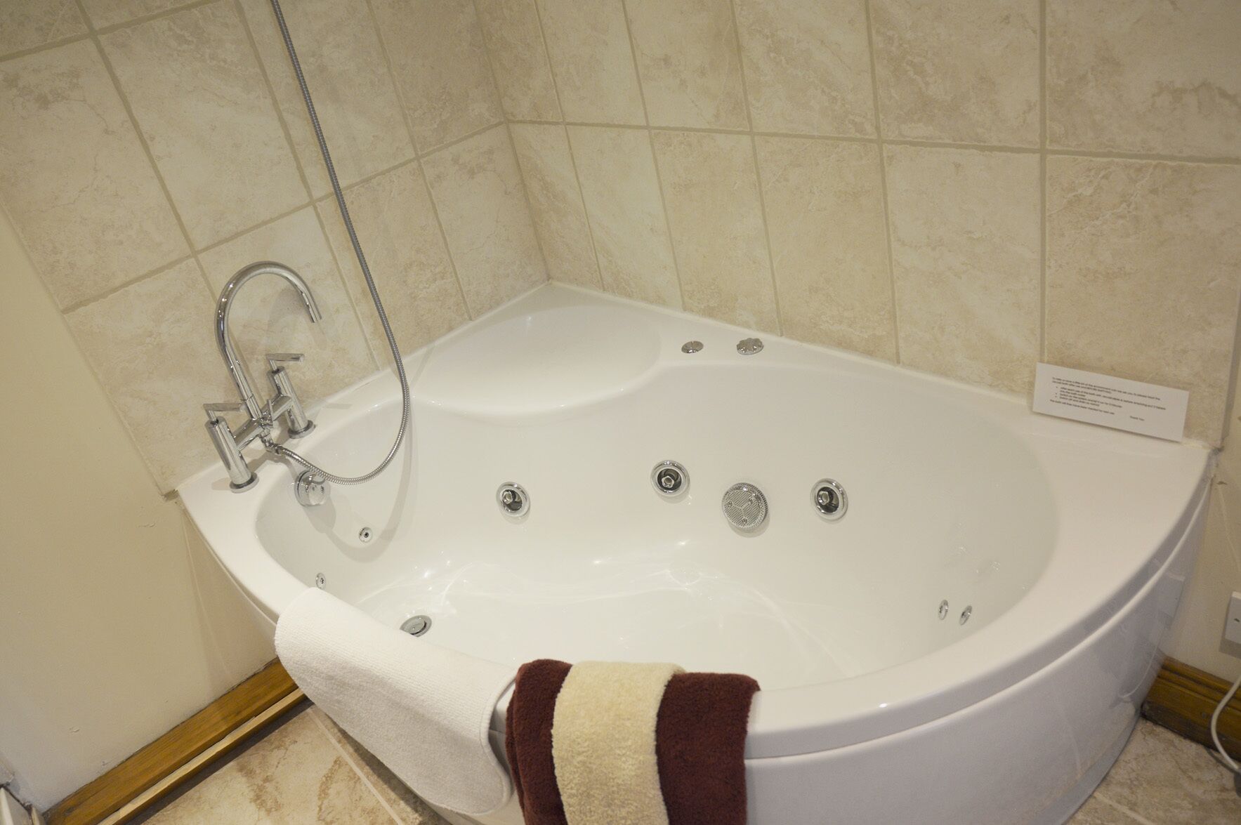 Baño con bañera blanca, ducha de mano y barra para toallas.