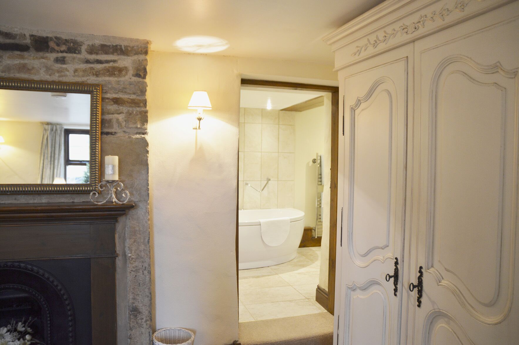A bathroom with a bathtub, a mirror, and a wall-mounted lamp.