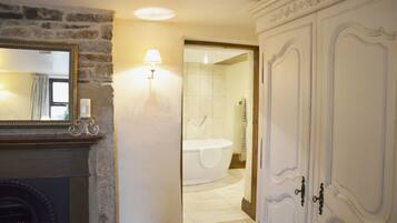 A bathroom with a bathtub, a mirror, and a wall-mounted lamp.