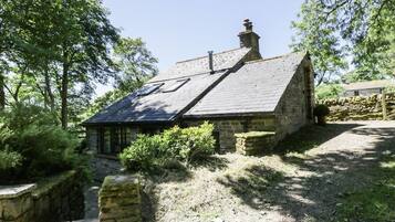 Une petite maison en pierre avec un toit en pente, une cheminée et une petite fenêtre.