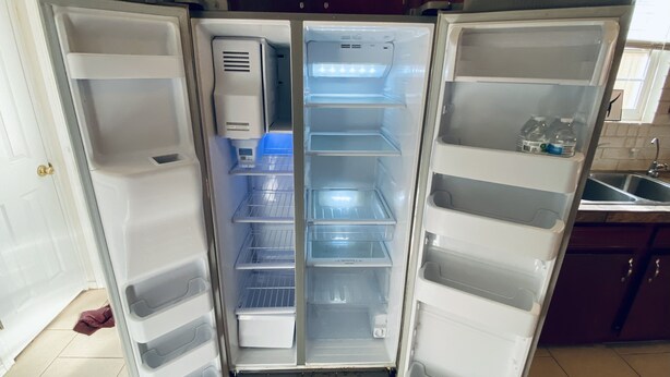 An open refrigerator with multiple shelves and a water dispenser. - String light condo with chic brick interior (Midland)