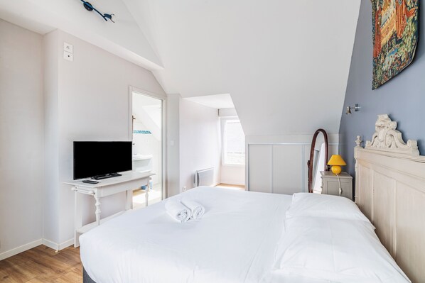 A bedroom with a large bed, a television on a white table, a mirror, and a decorative lamp. - La Maison des Fées - Three Bedroom House, Sleeps 6 (Pleudihen-sur-Rance)