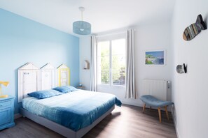 Une chambre à coucher comprenant un lit, une table de chevet, une chaise, une fenêtre et un radiateur.