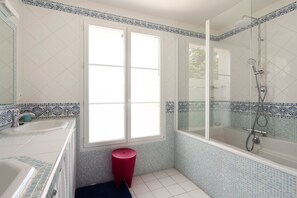 Une salle de bain avec une baignoire, une douche, un lavabo et une fenêtre.