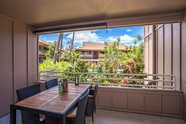 A balcony with a table and chairs, a railing, and a view of a building with palm trees.