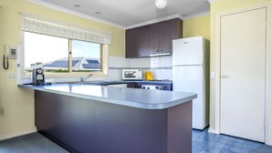 A kitchen with a central island, a microwave, a stove, and a refrigerator. - Alkira Inverloch Holiday (Inverloch)