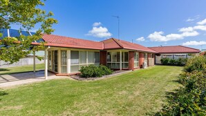 A two-story house with a red-tiled roof, large windows, and a fenced backyard. - Alkira Inverloch Holiday (Inverloch)