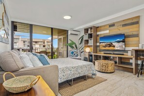 Una sala moderna con sofá, televisión, mesa de centro y comedor.