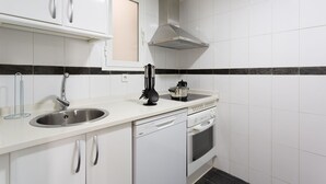 Una cocina moderna con armarios blancos, un lavamanos de acero inoxidable, un salpicadero blanco y negro, y un horno empotrado.