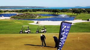 A golf course with a water hazard, sand bunkers, and a flag on the green.