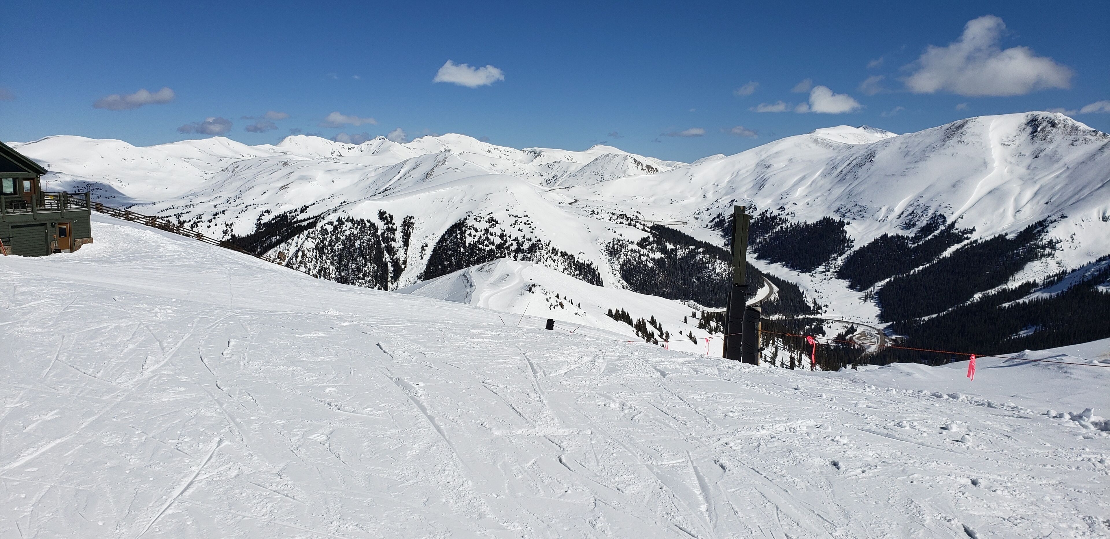 Eine verschneite Berglandschaft mit Seilbahn und Berghütte.