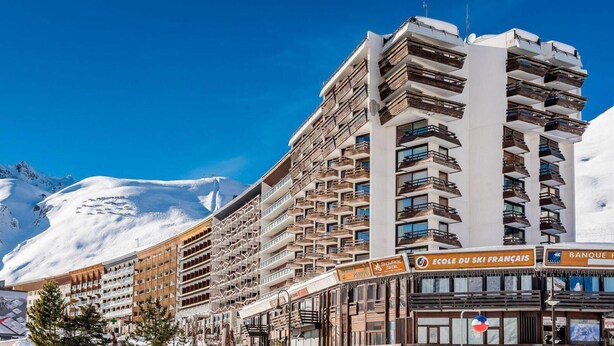 Un hotel con varios pisos, balcones y un cartel de estación de esquí.