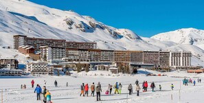 A ski resort with multiple buildings, including a large hotel with multiple floors and balconies, surrounded by snow-covered mountains. - 10m from resort center, 1st floor, tv, ski locker, 86m², Tignes (Tignes)