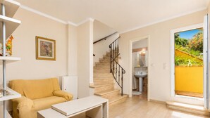 Un salon comprenant un canapé, une table basse et un escalier menant à une salle de bain.