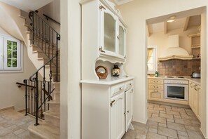 Classic design meets modern convenience in this inviting space, featuring a staircase, kitchen area with oven, and stylish cabinetry.