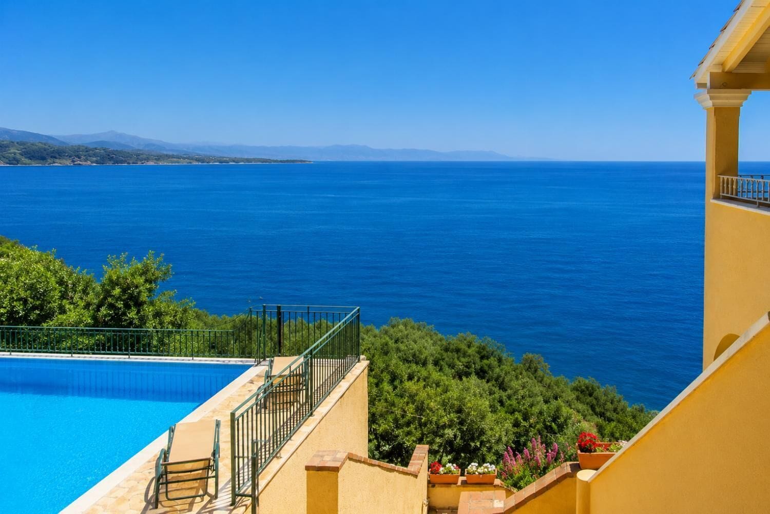 A clear blue pool with a view of the sea and distant mountains.