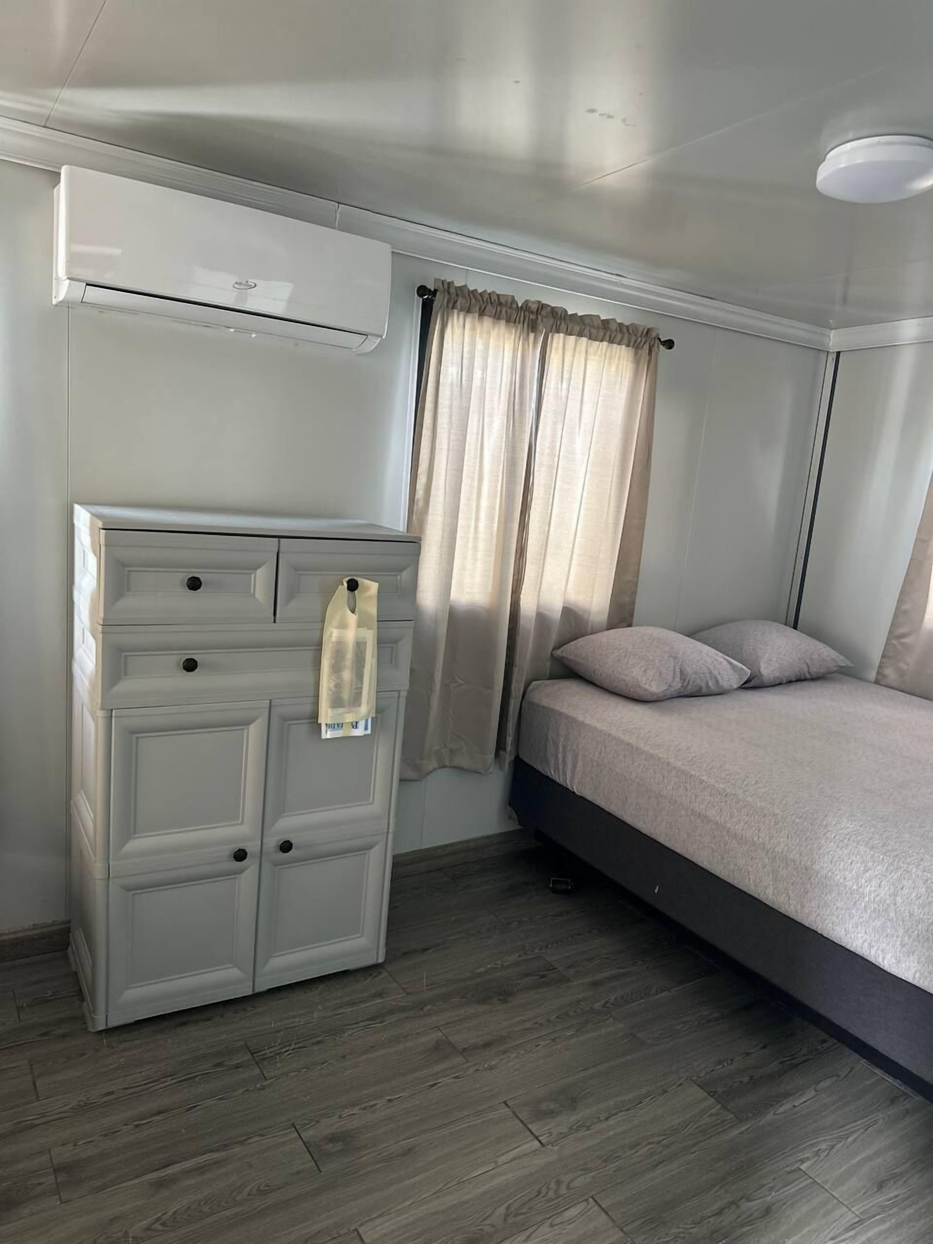 A bedroom with a bed, a wardrobe, and a window with curtains.