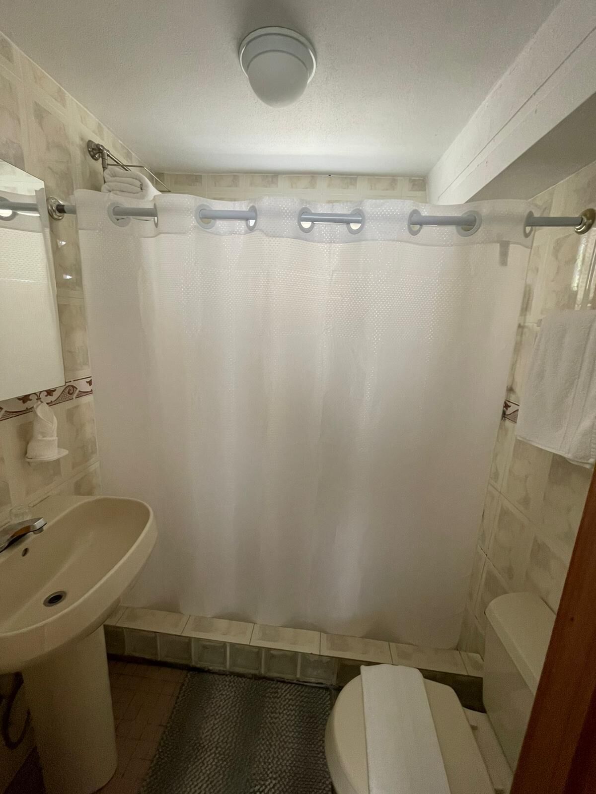 A bathroom with a shower curtain, a sink, and a toilet.