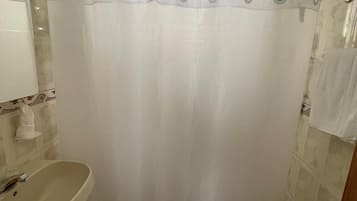 Un baño con cortina de ducha, lavamanos e inodoro.