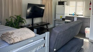 A compact room with a bed, a sofa, a TV, a kitchenette, and a dining area. - Las Casitas de Village (Carolina)