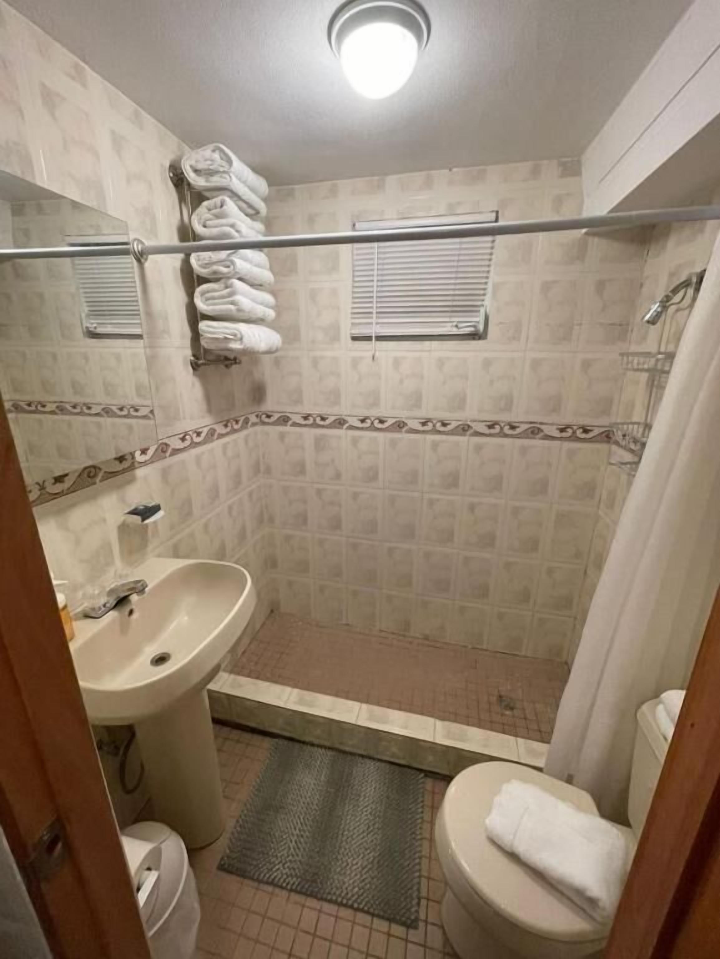 Ein kleines Badezimmer mit Dusche, Waschbecken und Toilette.