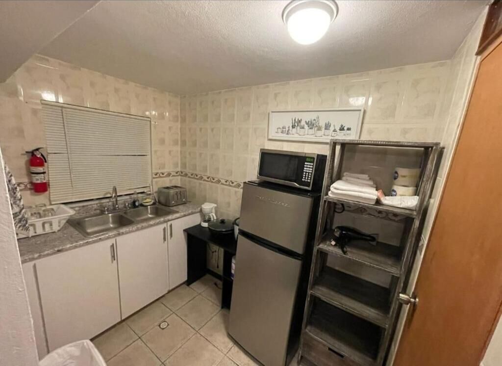 Una cocina compacta equipada con refrigerador, microondas, pileta y una pequeña mesada.