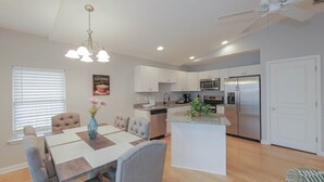 Una cocina moderna con armarios blancos, una isla central y electrodomésticos de acero inoxidable.