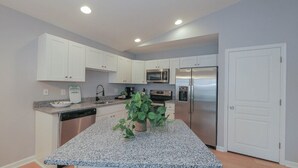 Una cocina moderna con armarios blancos, electrodomésticos de acero inoxidable y una encimera de granito.