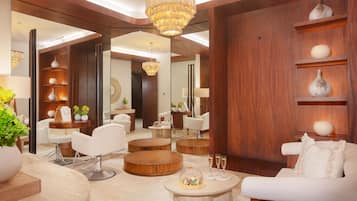 Un interior moderno con mesas redondas de madera, sofás blancos y una araña.