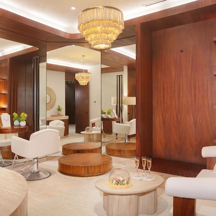 A modern interior with round wooden tables, white sofas, and a chandelier.