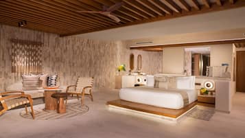 A modern bedroom with a wooden ceiling, a large bed, a bedside table, a mirror, and a seating area with a sofa and chairs.