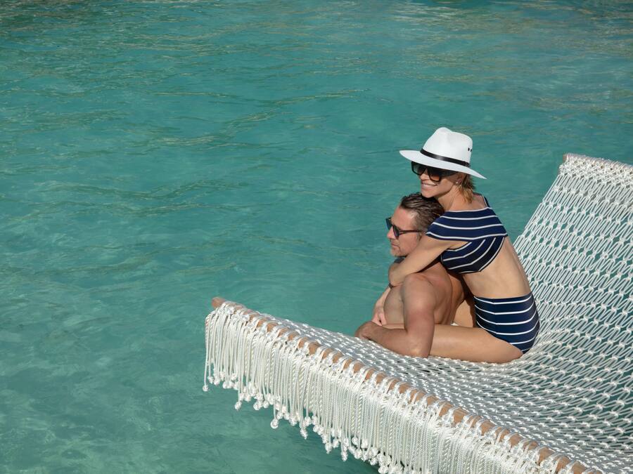 A wicker lounge chair by a clear turquoise pool.