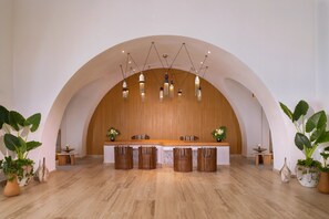A reception area with a wooden reception desk, multiple trash bins, and potted plants.