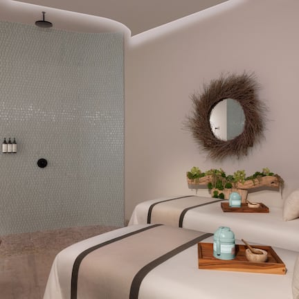 A modern bedroom with a large mirror, a wooden side table, and a bed with a headboard.