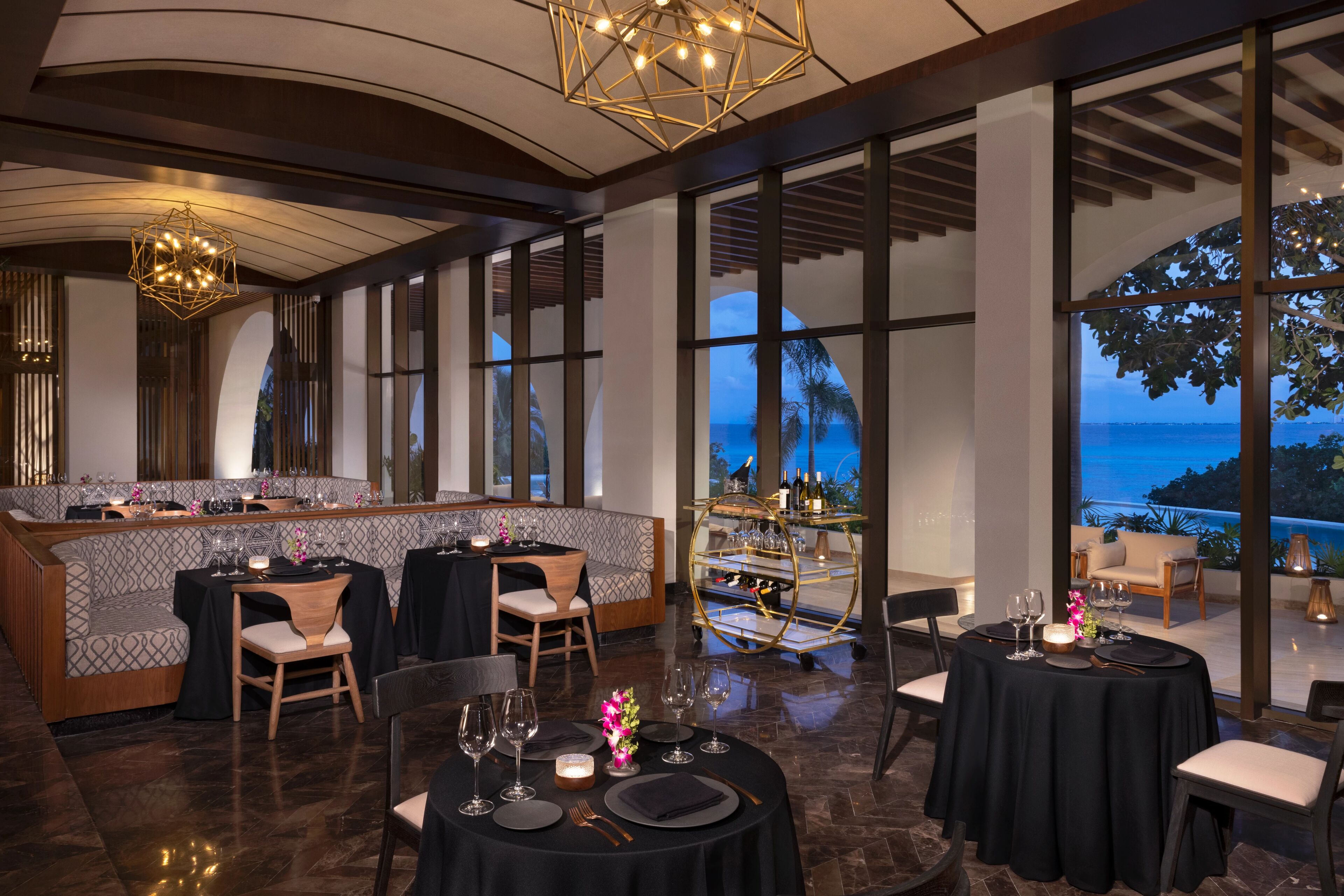 Ein Restaurant mit Barbereich, großen Fenstern mit Meerblick und einem modernen Innenraum.
