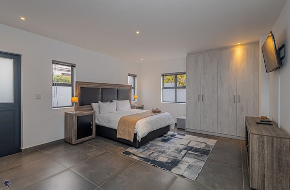 A modern bedroom with a large bed, built-in wardrobe, and a TV mounted on the wall. - Dalton's, Langebaan 10-sleeper (Langebaan)
