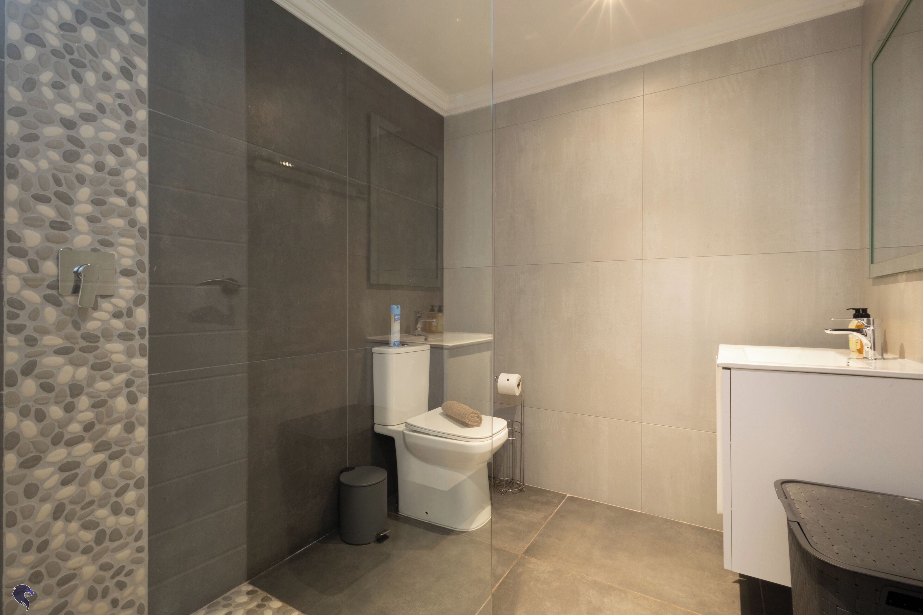 A modern bathroom with a shower, toilet, and sink.