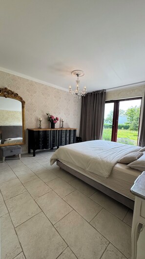 Une chambre à coucher avec un grand lit, une commode, un miroir et un lustre.