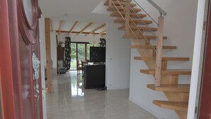 Un interior moderno con una escalera de madera, una zona de cocina y un espacio para comer.