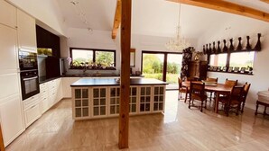 Una cocina amplia con una isla central, vigas de madera y un comedor con candelabro.