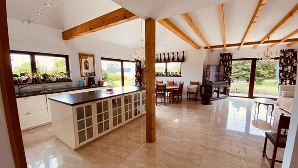 Una cocina amplia con una isla grande, vigas de madera y vistas al exterior.