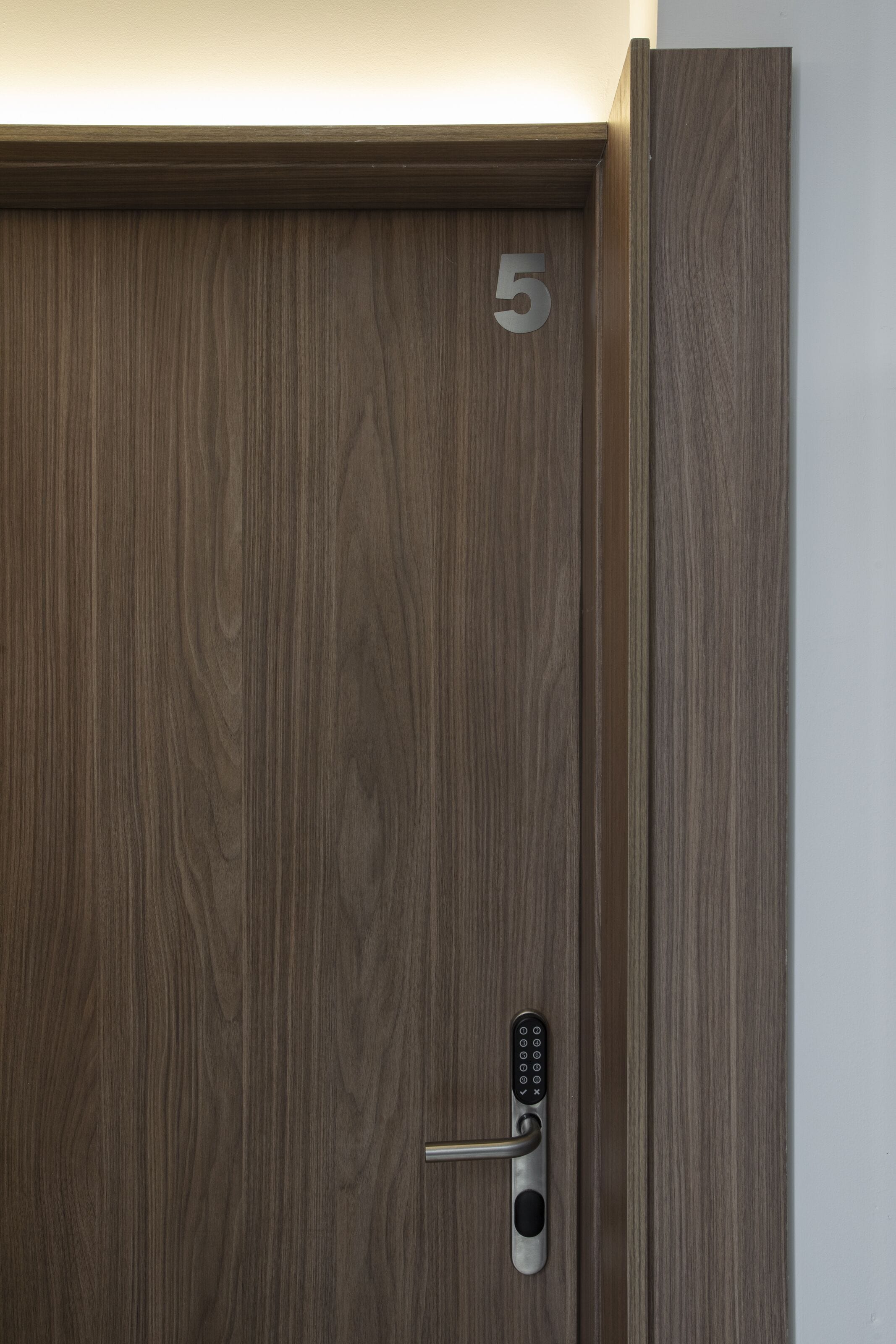 A wooden door with a numeric keypad lock and the number 5 on it.