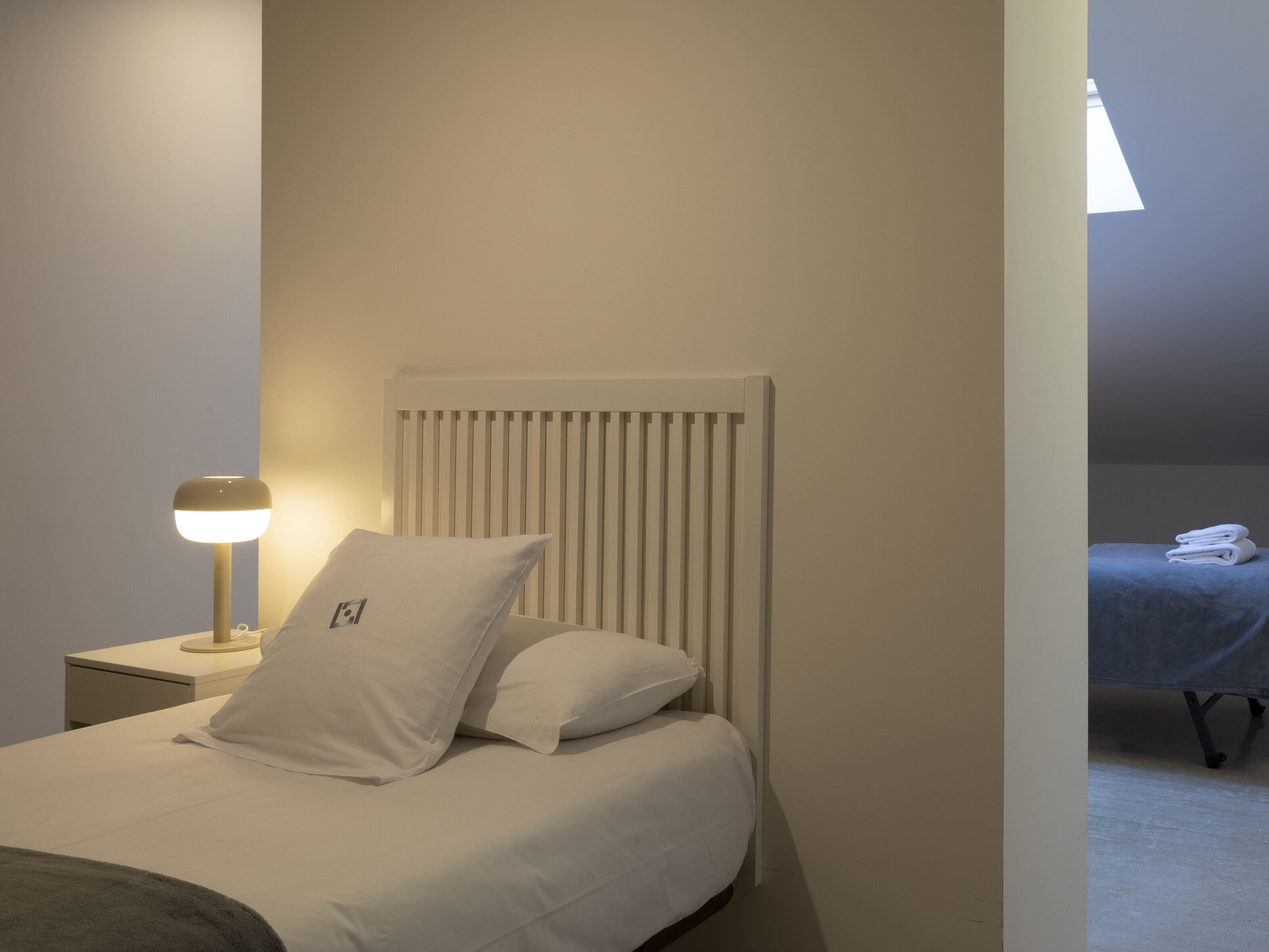A bedroom with a bed, a nightstand, a lamp, and a radiator.