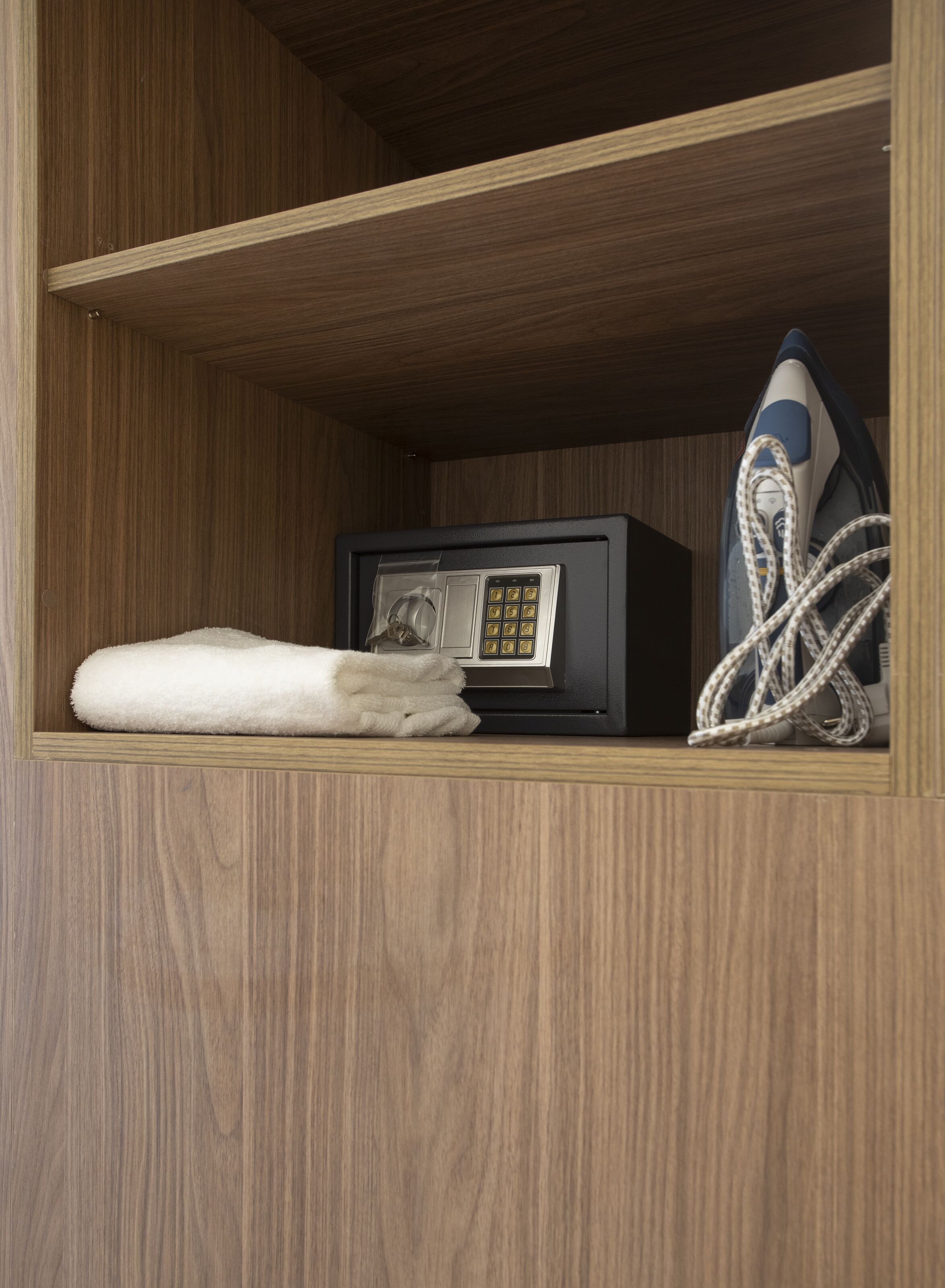 A wooden cabinet with a microwave, a white towel, and a coiled appliance cord.
